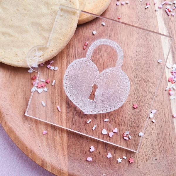 Embosser with love heart lock design on a wooden plate with valentines sprinkles and cookies