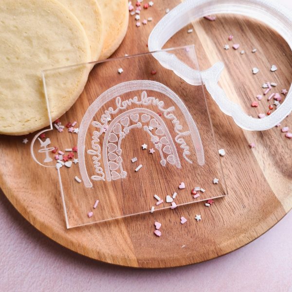 Embosser with a love boho rainbow design on a wooden plate with a cookie cutter, cookies and sprinkles